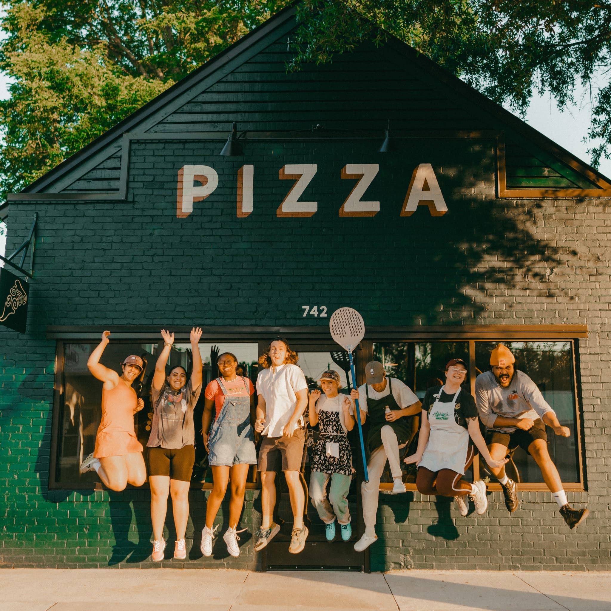 The Ghost Runner Pizza crew jumping out front of the shop at 742 Main St